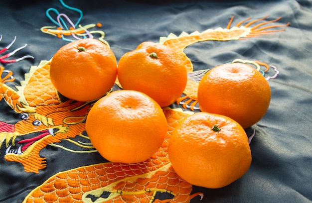 Photo nouvel an chinois, mandarines en tissu de soie avec dragon brodé