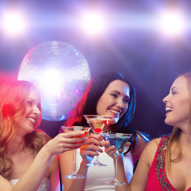 nouvel an, fête, amis, enterrement de vie de jeune fille, concept d'anniversaire - trois femmes en robes de soirée avec cocktails et boule disco
