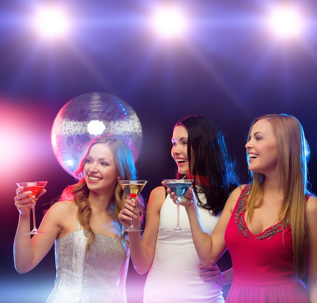 nouvel an, fête, amis, enterrement de vie de jeune fille, concept d'anniversaire - trois femmes en robes de soirée avec cocktails et boule disco