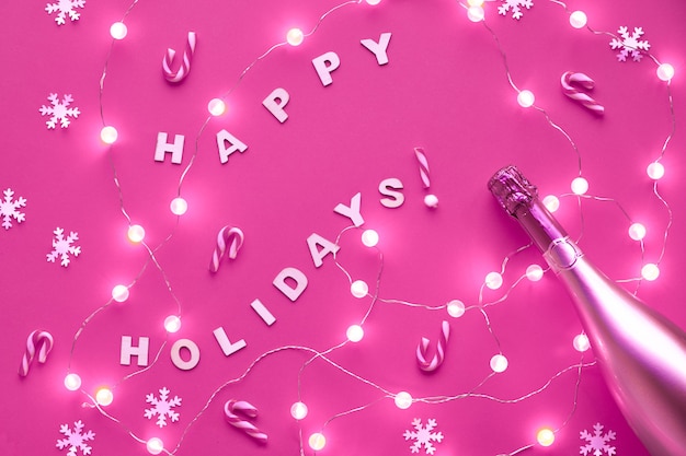 Nouvel an ou motif de Noël plat poser vue de dessus mur avec texte "Joyeuses fêtes". Flocons de neige en papier, guirlande de boule de verre allume mur rose. Mur teinté monochrome brillant à la mode.