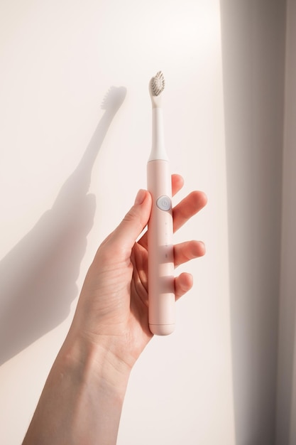 Nouvelle brosse à dents à ultrasons moderne dans la main de la femme. Modèle de mâchoire et fournitures de soins dentaires. Hygiène bucco-dentaire, santé dentaire et gingivale, dents saines. Produits dentaires Brosse à dents à vibration ultrasonique.