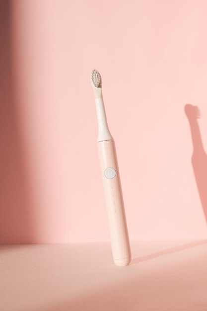 Nouvelle brosse à dents à ultrasons moderne fournitures de soins dentaires avec des pierres blanches sur fond pastel rose ou...