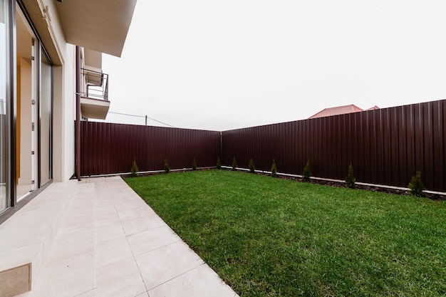 Une nouvelle cour dans la maison avec de l'herbe verte et une clôture