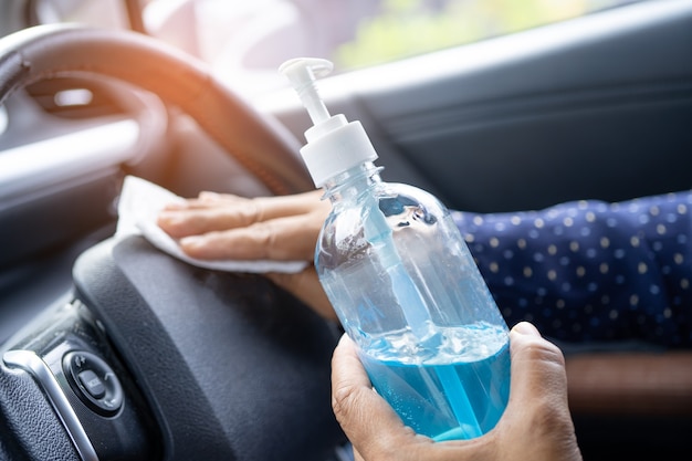 Nouvelle femme de travail asiatique normale propre dans la voiture en appuyant sur le gel désinfectant à l'alcool bleu