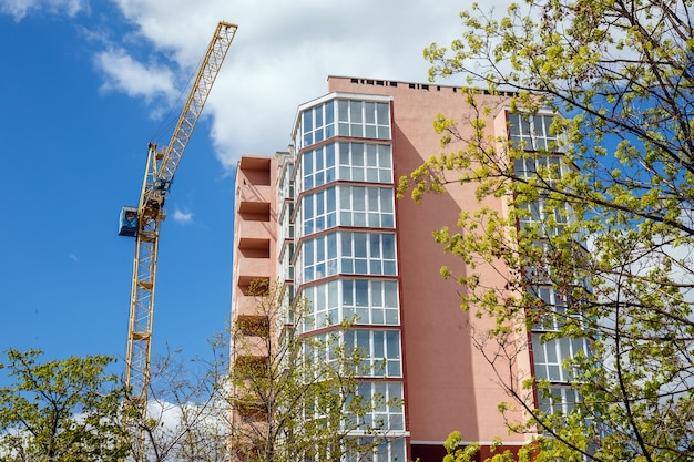 Nouvelle maison d&#39;habitation moderne et arbres verts sur fond de ciel bleu nuageux à la journée ensoleillée.