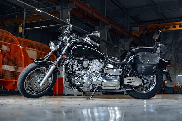 Nouvelle moto brillante debout dans un hangar sombre