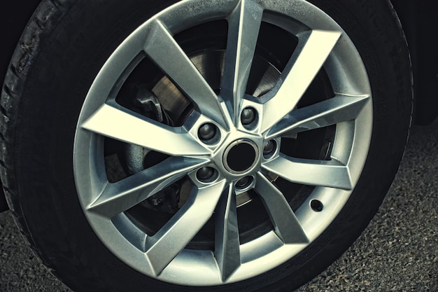 Nouvelle roue de voiture avec roue en alliage Détail de la voiture sur un fond d'asphalte gris