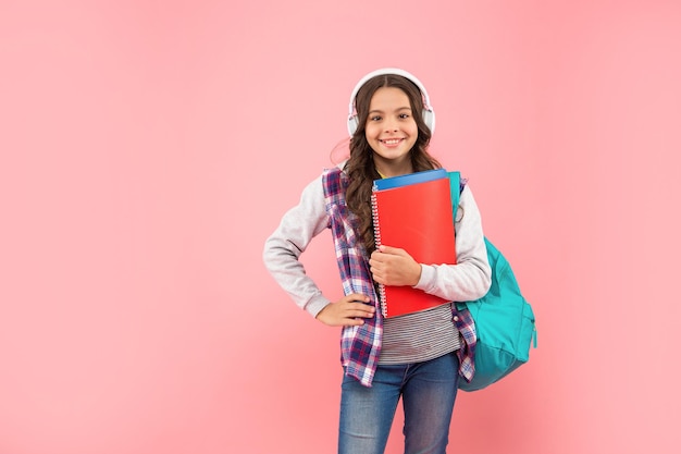 Nouvelle technologie. développement de l'enfance. l'enfant dans les écouteurs tient un classeur et un sac à dos. éducation en ligne. retour à l'école. heureuse adolescente dans les écouteurs. écouter de la musique. espace de copie.