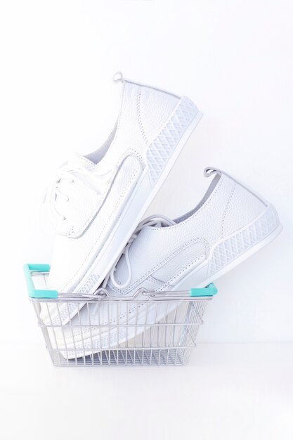 Nouvelles baskets blanches dans un panier sur fond blanc