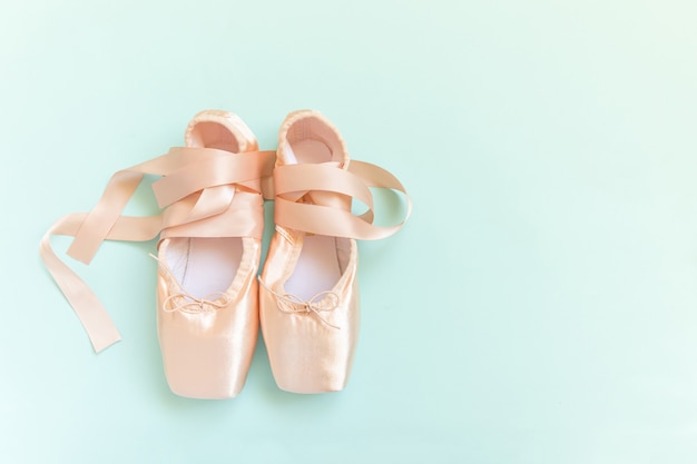 Nouvelles chaussures de ballet beige pastel avec ruban de satin isolé sur fond bleu
