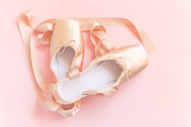 Nouvelles chaussures de ballet beige pastel avec ruban de satin isolé sur fond rose