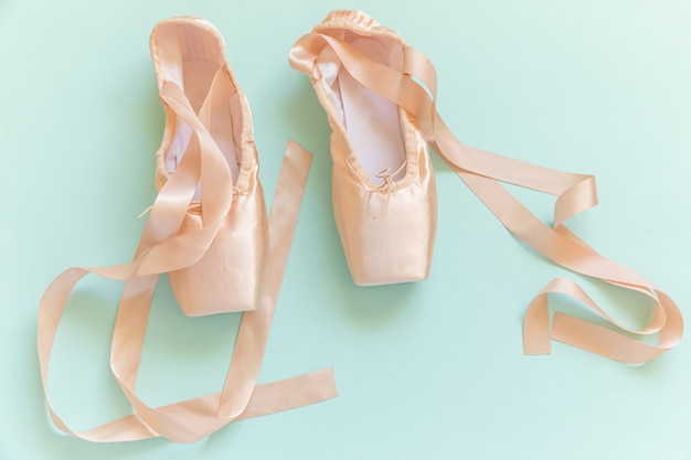 Nouvelles chaussures de ballet beige pastel avec ruban de satin isolé sur tableau bleu