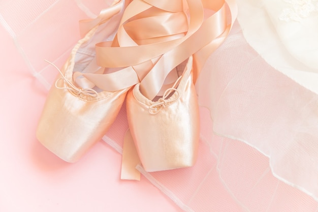 Nouvelles chaussures de ballet beige pastel avec ruban de satin et jupe tutut isolé sur fond rose