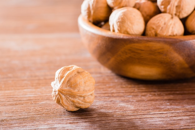 Noyer dans la coquille se trouve sur une table en bois à l'arrière-plan d'une assiette avec des noix