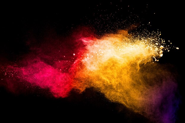 Nuage d'explosion de poudre jaune rouge sur fond noir. Figer le mouvement des éclaboussures de particules de poussière de couleur rouge jaune.