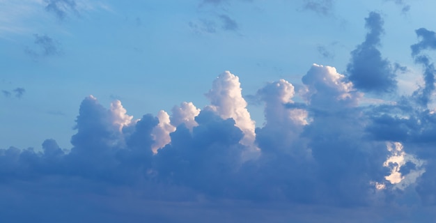 Nuages blancs et foncés ensoleillés dans le ciel bleu