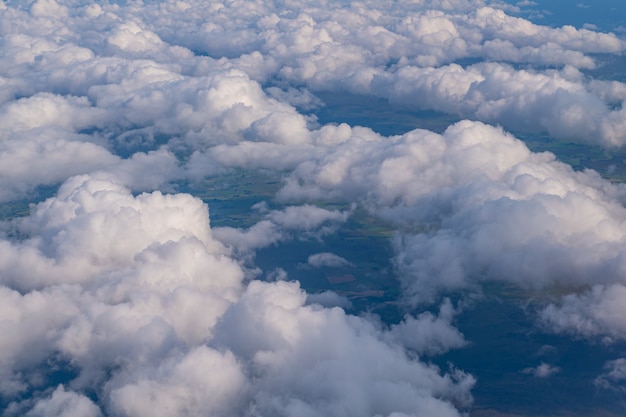 Nuages blancs et moelleux vue du ciel avec terre visible ci-dessous