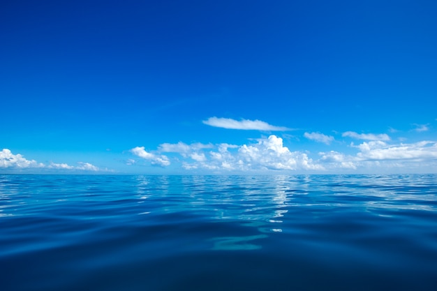 Nuages sur un ciel bleu au-dessus d&#39;une mer calme avec reflet du soleil