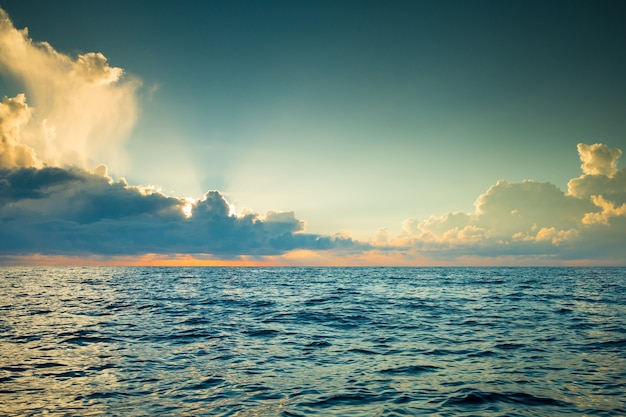 Nuages sur le ciel bleu au-dessus de la mer calme avec la réflexion du soleil