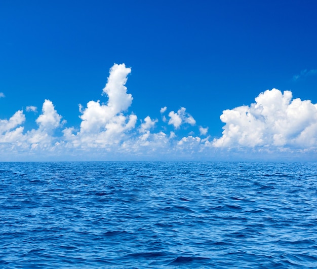 Nuages ​​sur un ciel bleu sur une mer calme avec la réflexion de la lumière du soleil