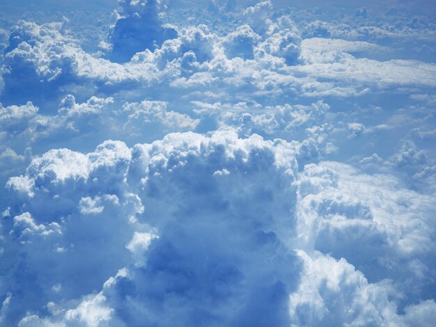 Photo nuages et ciel depuis la fenêtre de l'avion formation de cumulus blancs dans le ciel bleu