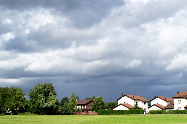 Nuages dramatiques gris foncé et jolies petites maisons