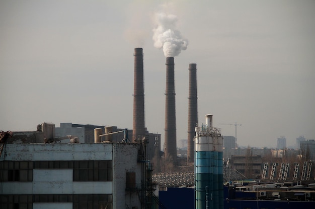 Des nuages de fumée provenant des cheminées d'une usine industrielle polluent l'air dans une zone suburbaine