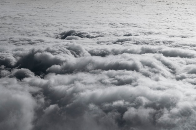 Nuages hauts dans le ciel, nuages blancs et gris duveteux depuis la fenêtre de l'avion