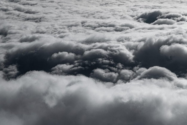 Photo nuages hauts dans le ciel, nuages blancs et gris duveteux depuis la fenêtre de l'avion