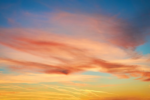 Nuages poreux colorés au coucher du soleil sur ciel bleu.