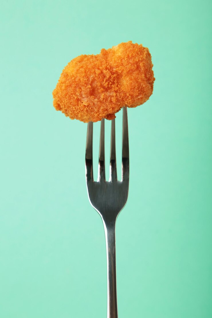 Nugget de poulet sur une fourchette sur fond de menthe Photo verticale