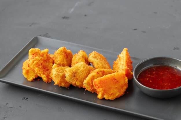 Nuggets de poulet frits servis avec sauce chili sur fond gris