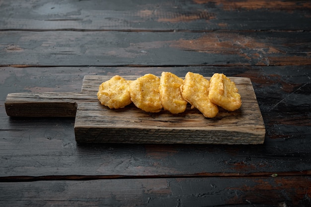 Nuggets de poulet frits sur la vieille table en bois sombre.