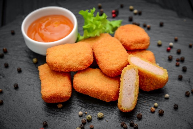 Nuggets De Poulet De Restauration Rapide Avec Du Ketchup, Contre Une Surface Sombre