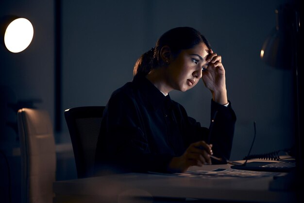 Photo nuit de stress et femme d'affaires sur ordinateur travaillant sur la planification du projet et la date limite de la stratégie santé mentale de l'épuisement professionnel et travailleuse pensant dans un bureau sombre avec des maux de tête fatigués et surmenés