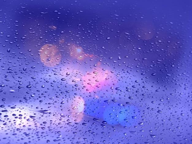 la nuit de la ville gouttes de pluie sur les fenêtres et la circulation dans la rue soir modèle de saison des pluies floue