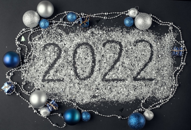 Numéro 2022 écrit sur des paillettes éparses et une décoration de Noël sur fond sombre