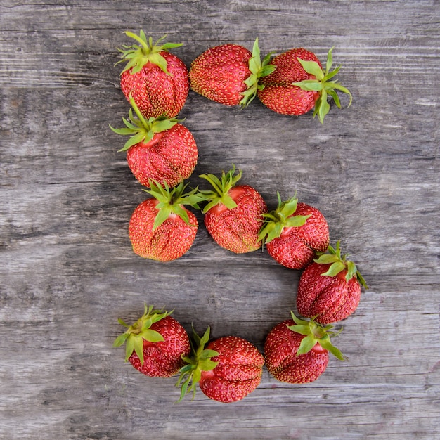 Numéro 5 de fraises sur fond de bois