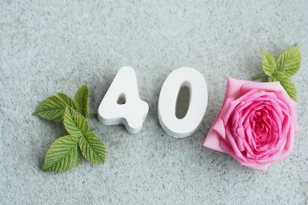 Photo numéro de béton 40 et une belle rose avec des pétales et des coeurs sur fond gris béton.