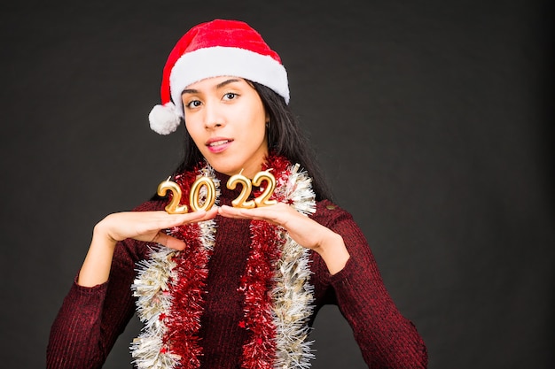 Numéro de célébration du nouvel an jeune femme latine avec bonnet de noel bonne année