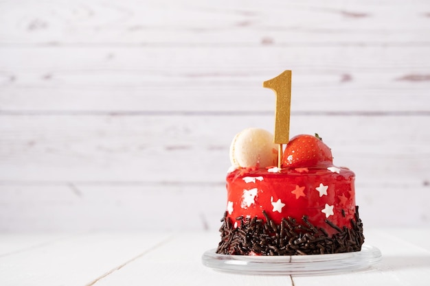 Le numéro un sur un gâteau d'anniversaire rouge sur fond clair