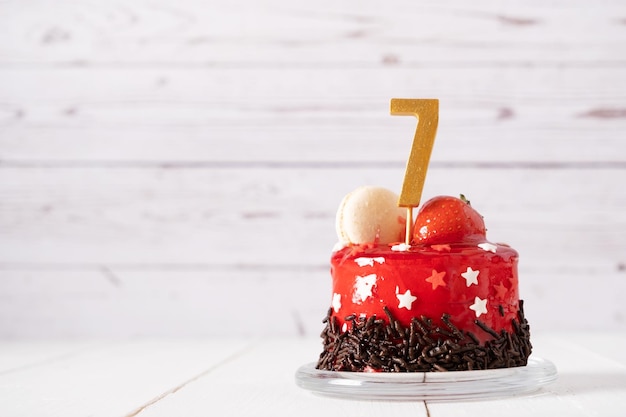 Le numéro sept sur un gâteau d'anniversaire rouge sur fond clair