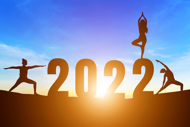 Numéros de bonne année 2022, Silhouette femme pratiquant le yoga lever du soleil tôt le matin sur l'arrière-plan de l'horizon, concept de santé et de bonne année.