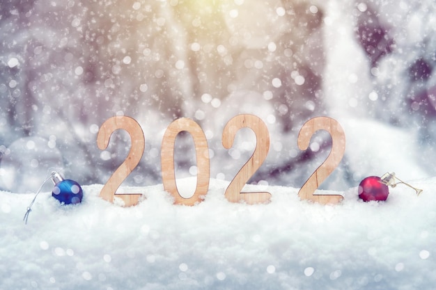 Numéros du nouvel an en contreplaqué 2022 dans une congère à l'extérieur avec des boules de Noël