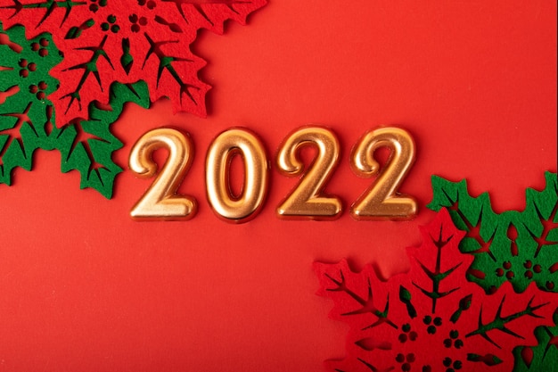 Numéros d'or 2022 sur fond rougeBelles feuilles de houx décoratives autour