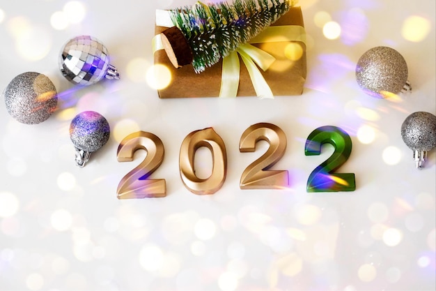 Numéros d'or de bonne année à plat 2022 sur fond clair avec bokeh, carte de voeux avec cadeaux artisanaux