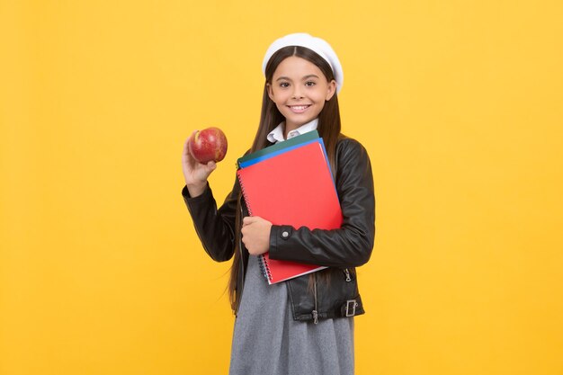 Nutrition de l'enfant Une adolescente heureuse tient une pomme et des livres Nutrition scolaire Régime végétarien Fournir des aliments sains Petit-déjeuner de retour à l'école