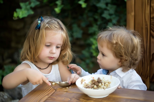 La nutrition des enfants, la fille qui nourrit le bébé garçon, la soeur nourrit les relations entre le frère et l'enfant