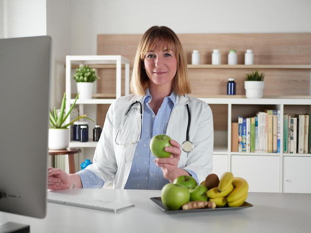 Nutritionniste féminine tenant une pomme verte dans un studio de bureau