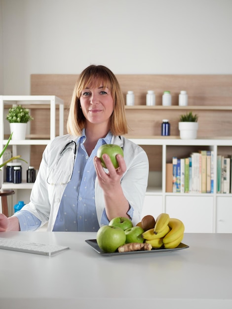 Nutritionniste féminine tenant une pomme verte dans un studio de bureau